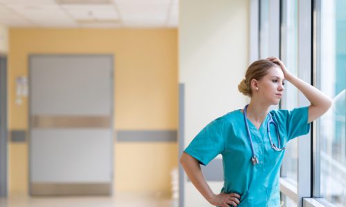 Tired female nurse in hospital corridor