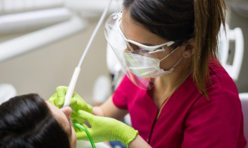 Dentist cleaning teeth of woman